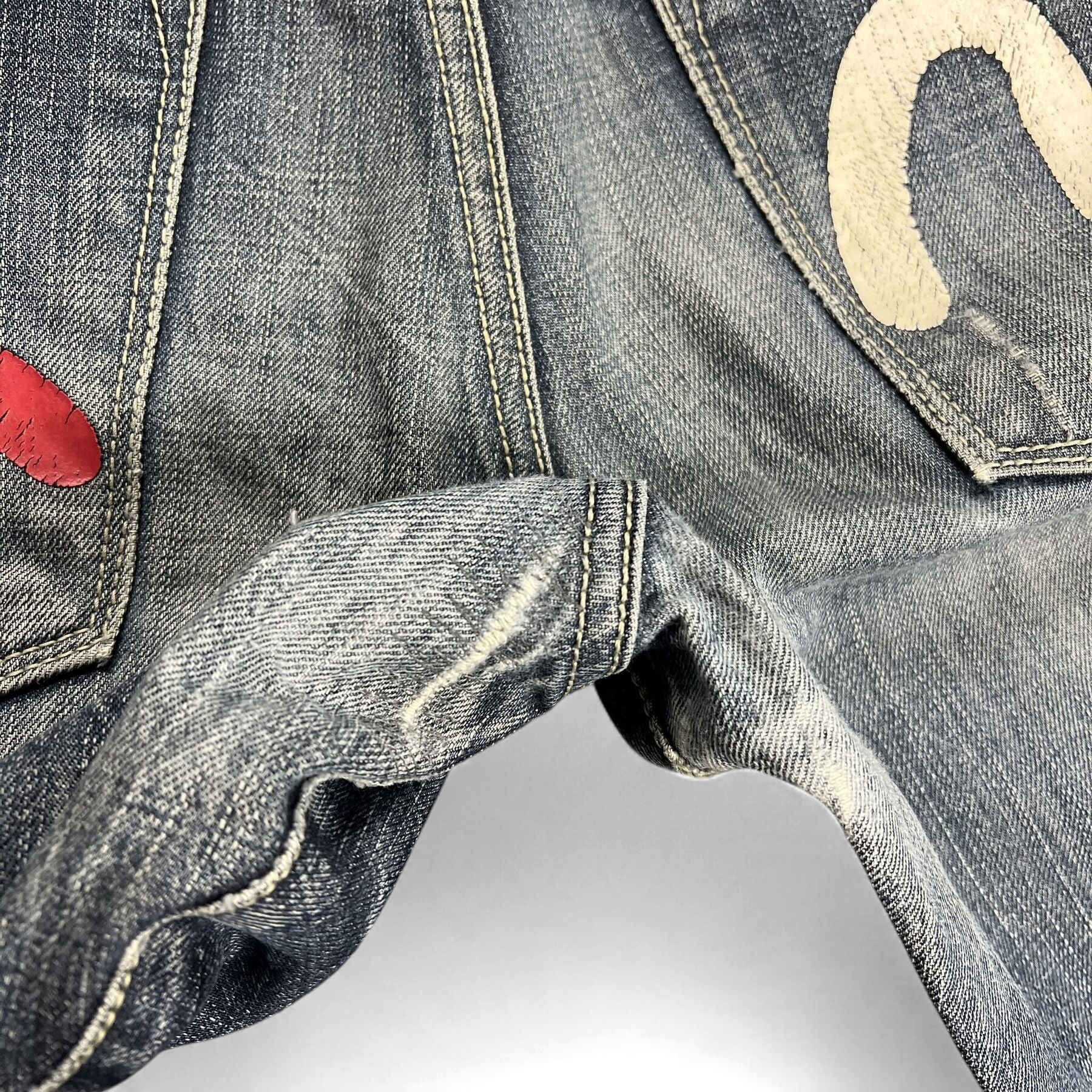 TWC Vintage Evisu Jeans mit klassischem Denim-Stoff, weißem Logo-Print und rotem Detail auf der Gesäßtasche