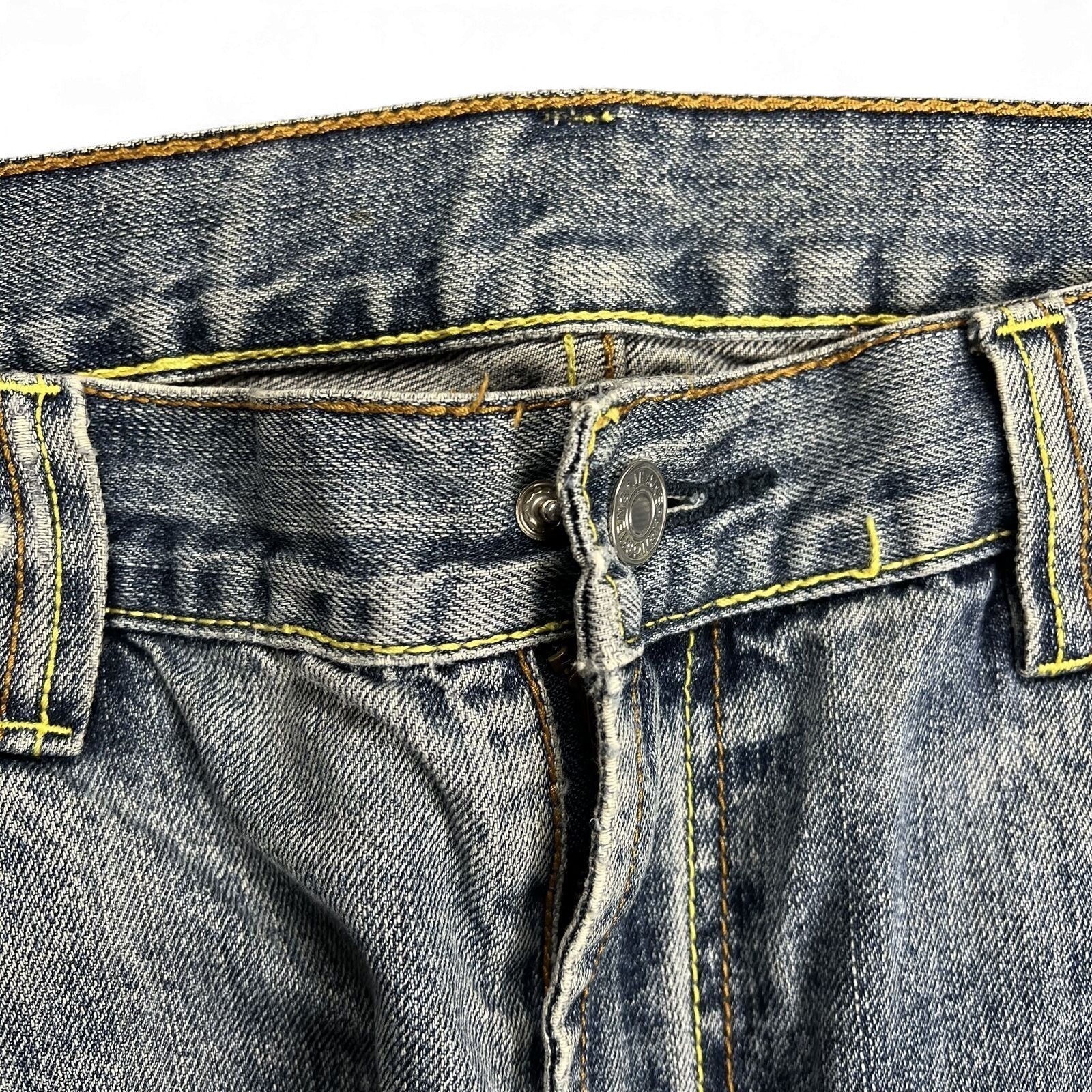 TWC Vintage Jeans aus blauem Denim mit markanten gelben Kontrastnähten und Metallknopf am Bund