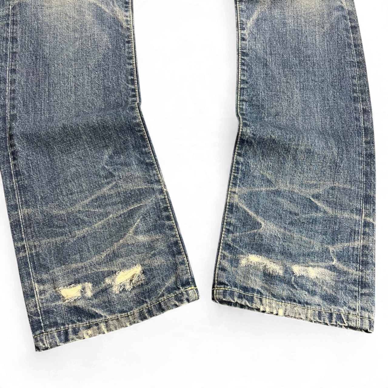 TWC Vintage distressed blue denim jeans with whiskering and frayed hem details on a white background